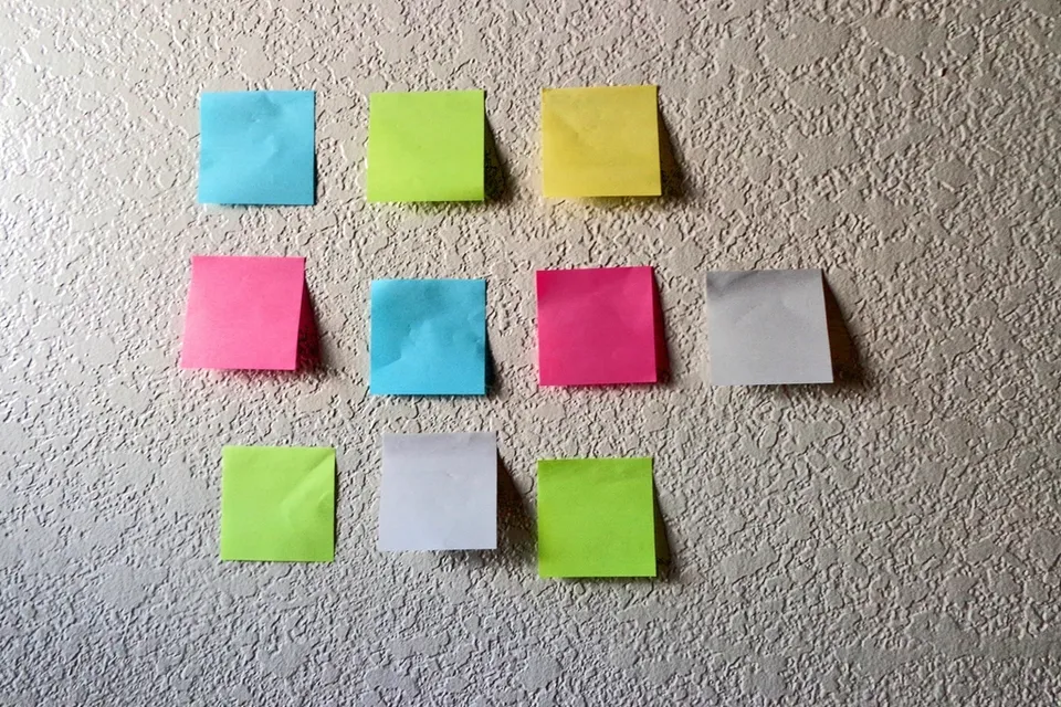 Blank sticky notes arranged in rows on a white wall