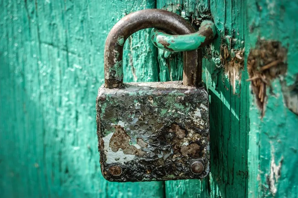 An old padlock on a weathered green door