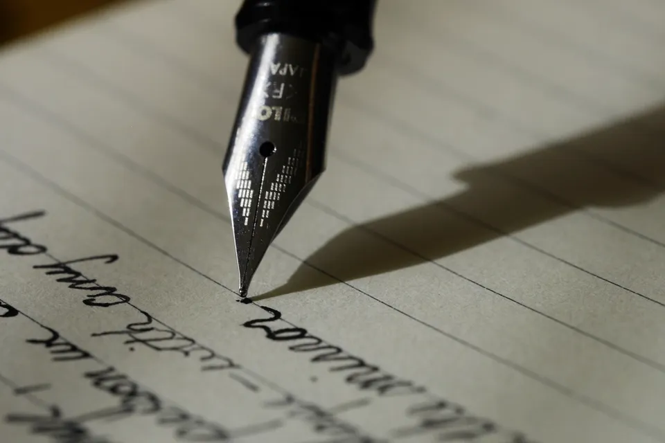 A fountain pen writing by hand in a lined notebook